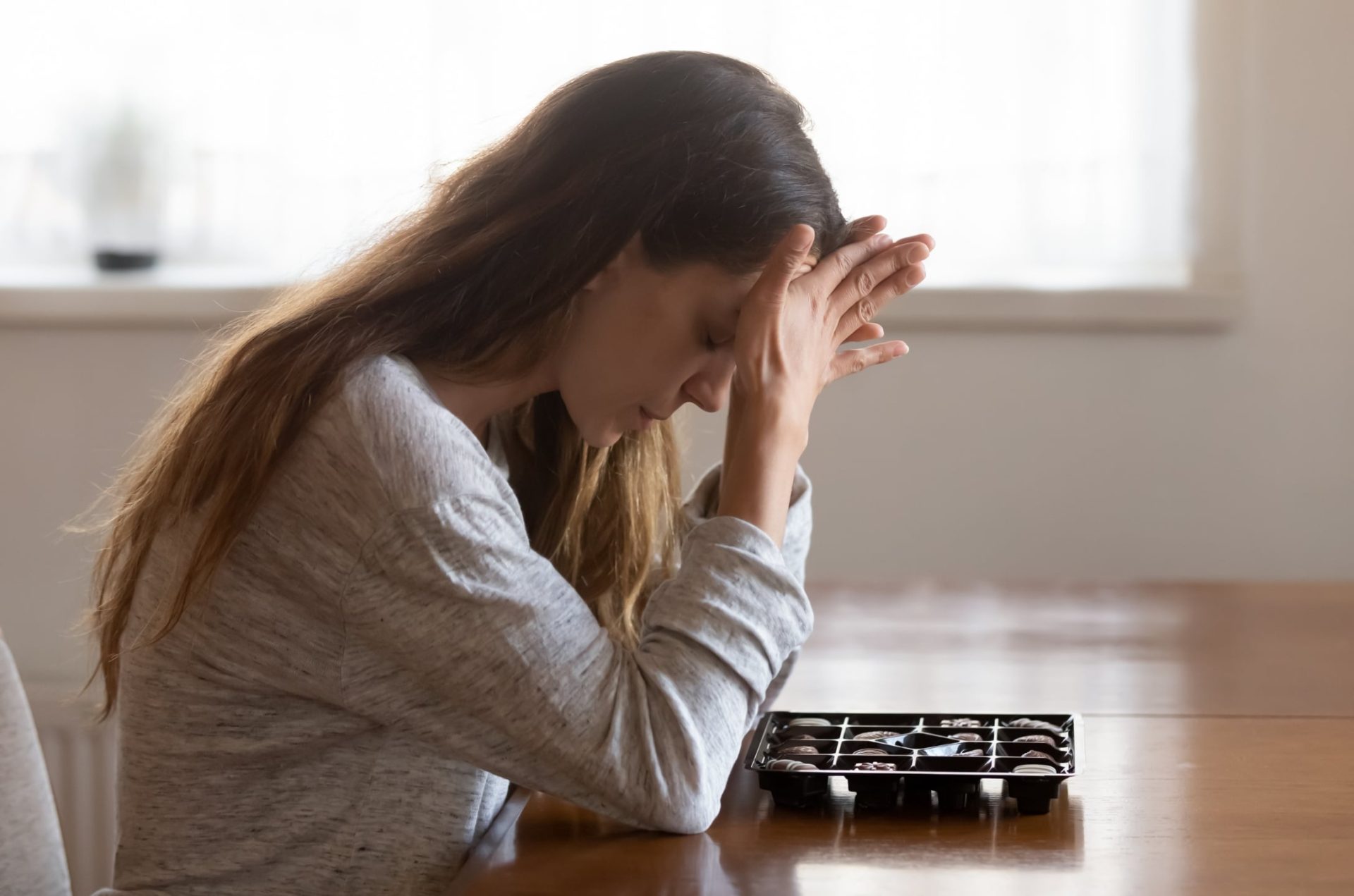 girl sitting at the table anxious to eat chocolate as she is struggling with an eating disorder