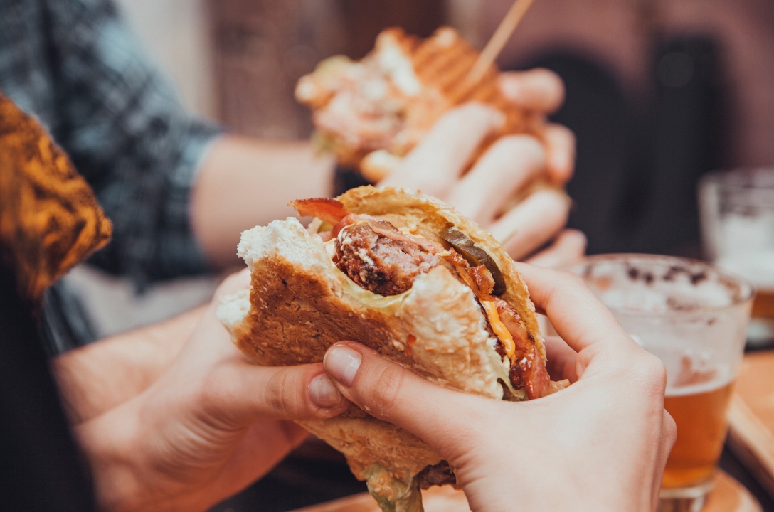 holding a burger with two hands, one mouthfull has been taken