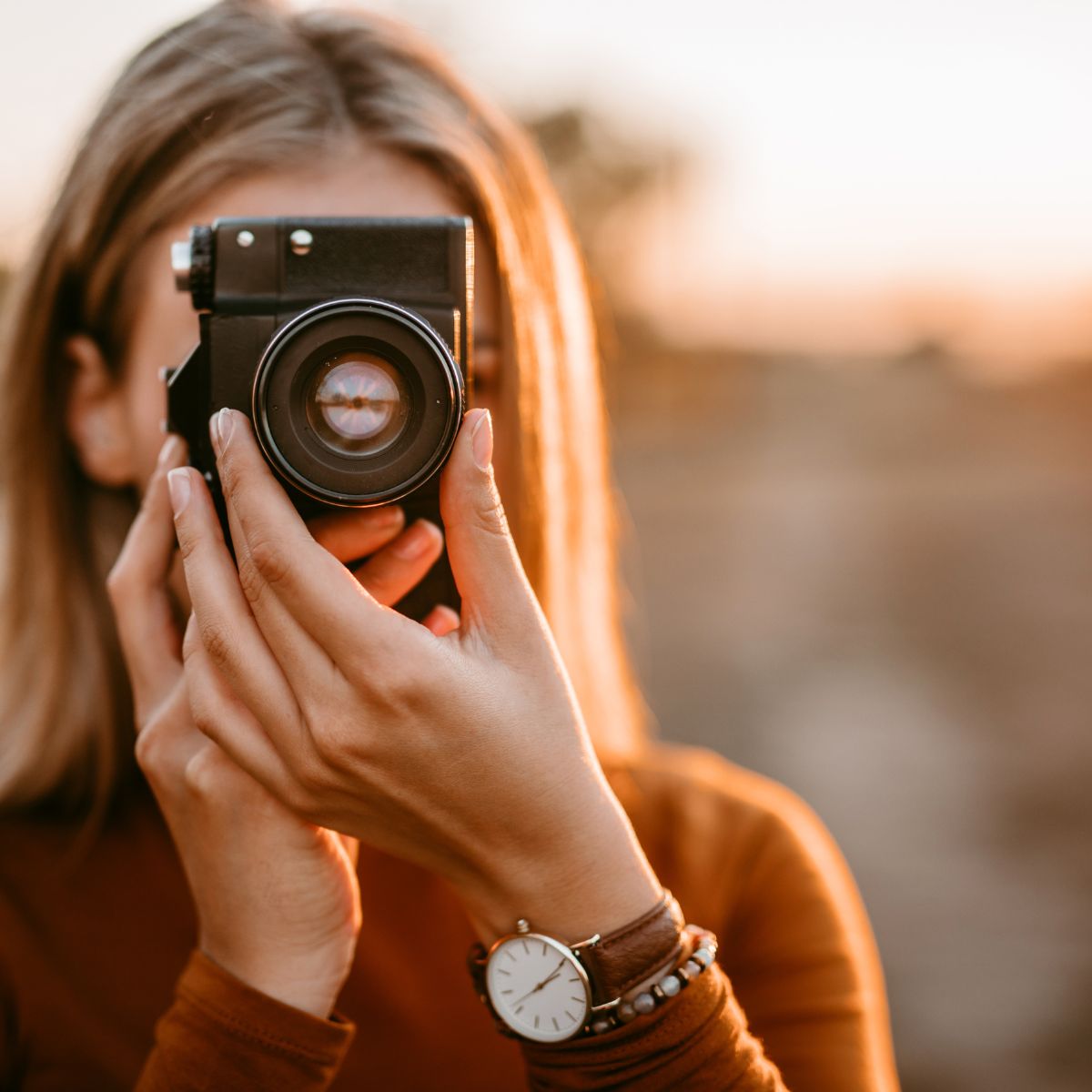 Girl with blonde hair holding up a camera and taking a photo